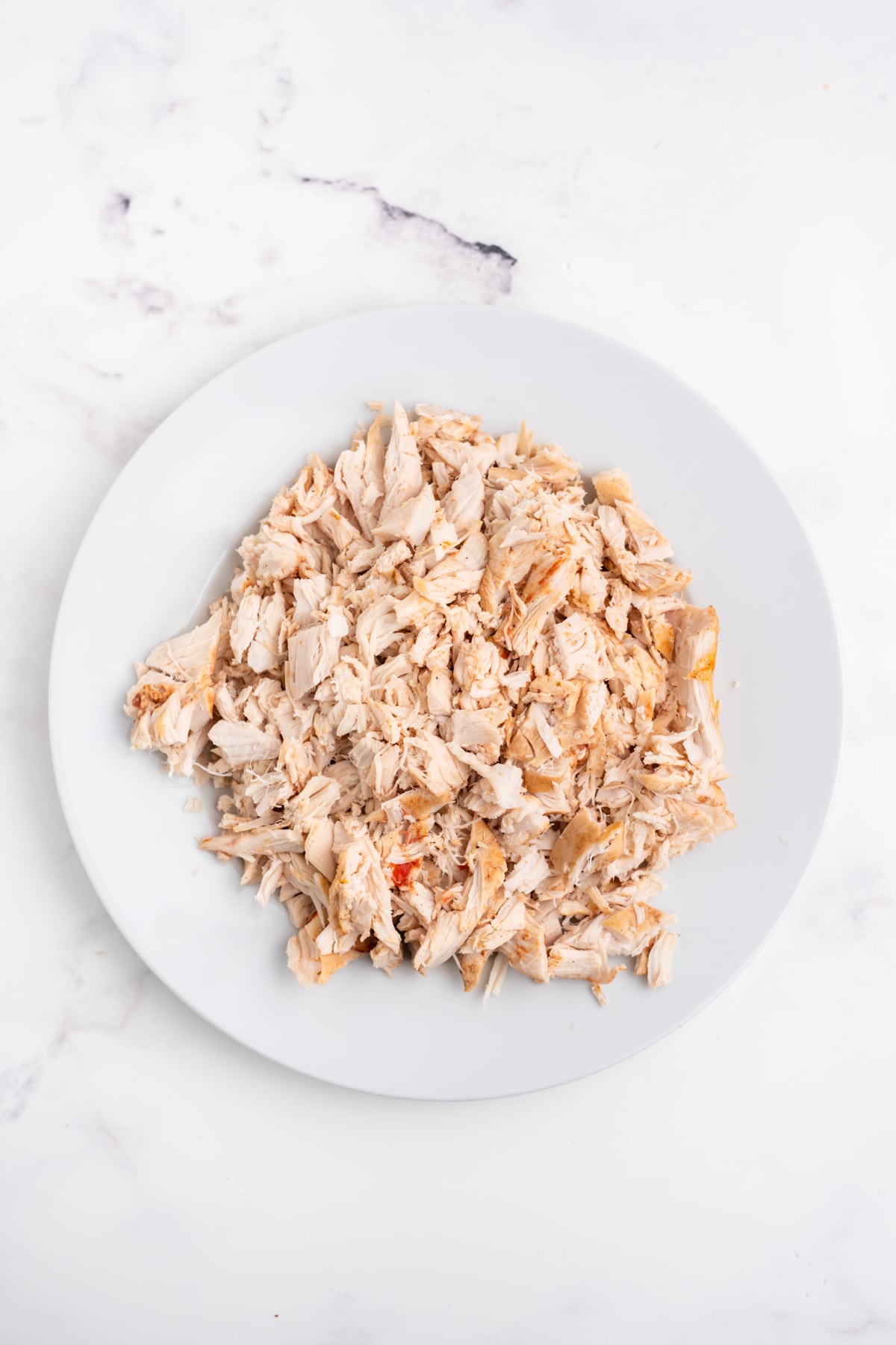 Chicken shredded on a plate.