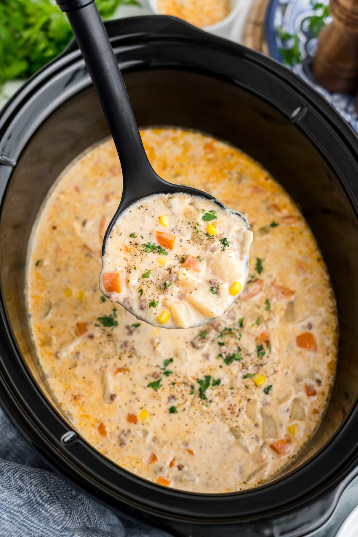 Creamy hamburger and potato soup being ladled out of the slow cooker.