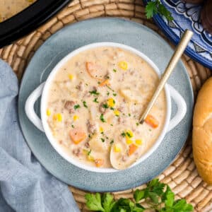 A bowl of crockpot creamy hamburger and potato soup witha. spoon resting in the bowl.