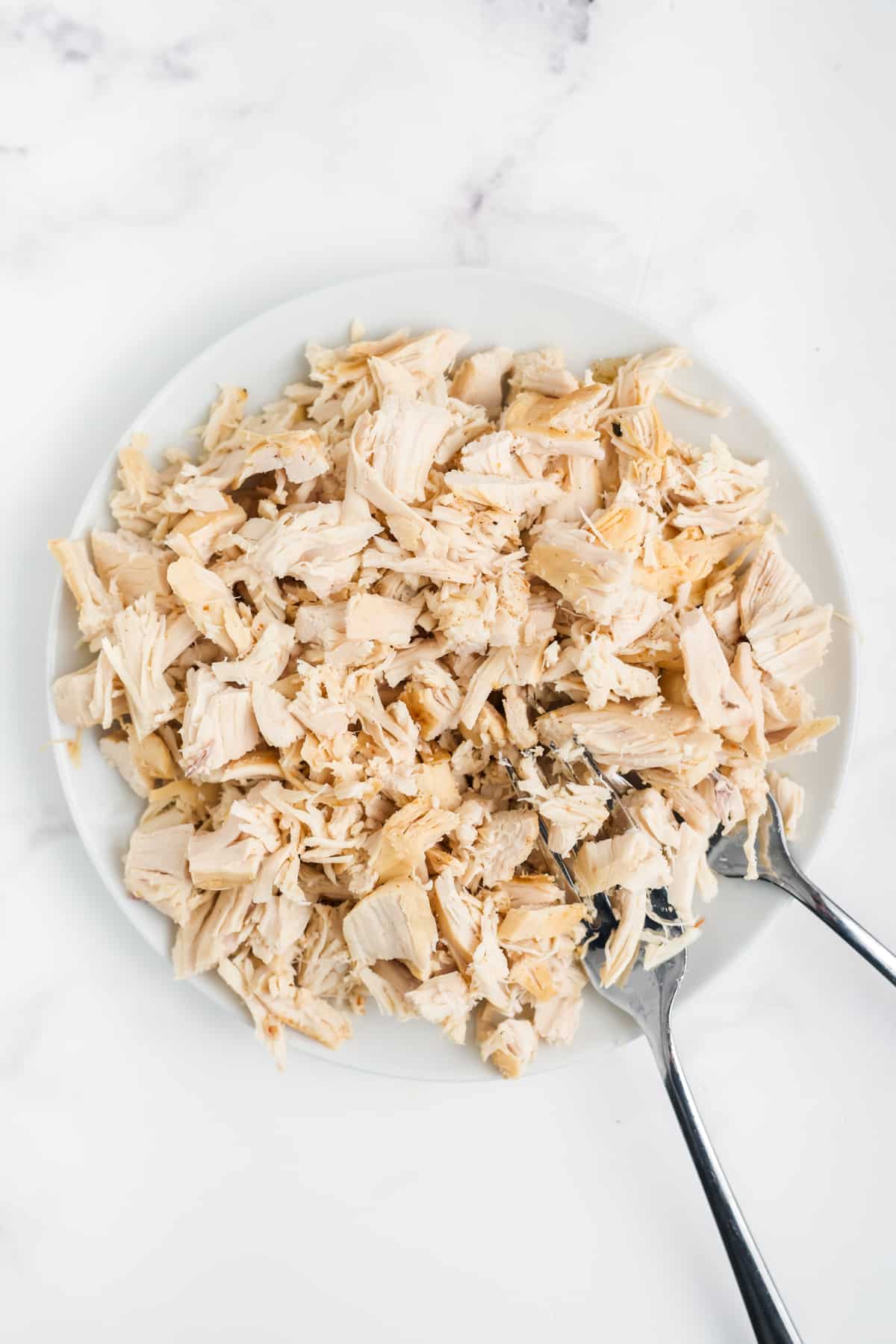 Cooked chicken shredded on a plate.