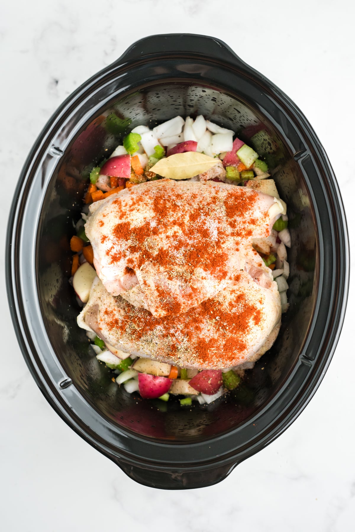 Chicken and seasonings added on top of the vegetables. 