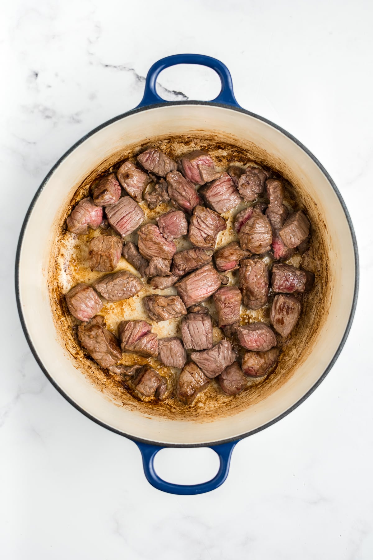 Chunks of beef being browned in a pot.