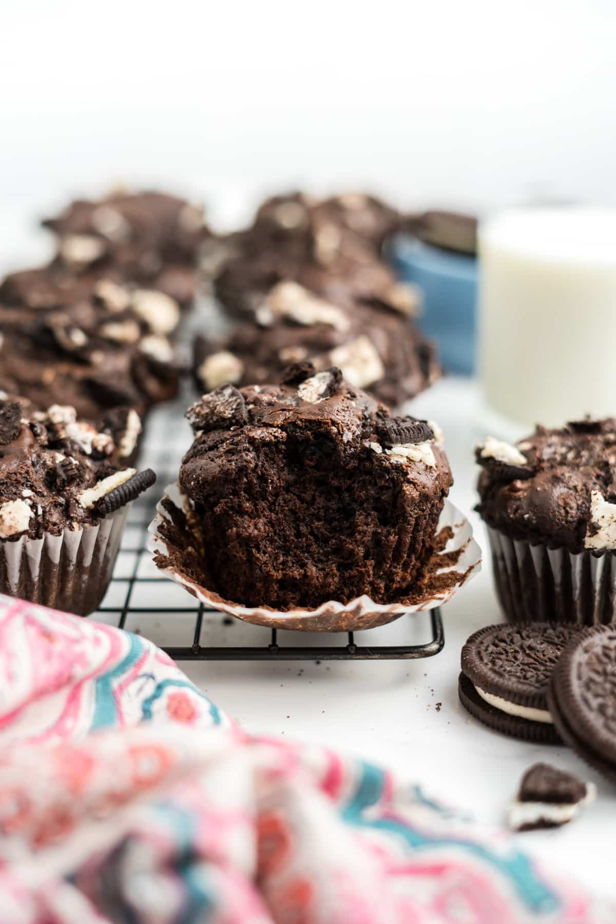 Oreo muffins on a cooling rack with a bite taken from the one in front. 