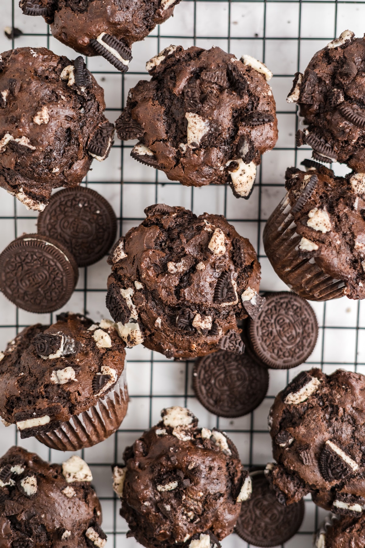 Oreo muffins on a cooling rack with Oreo cookies scattered around. 