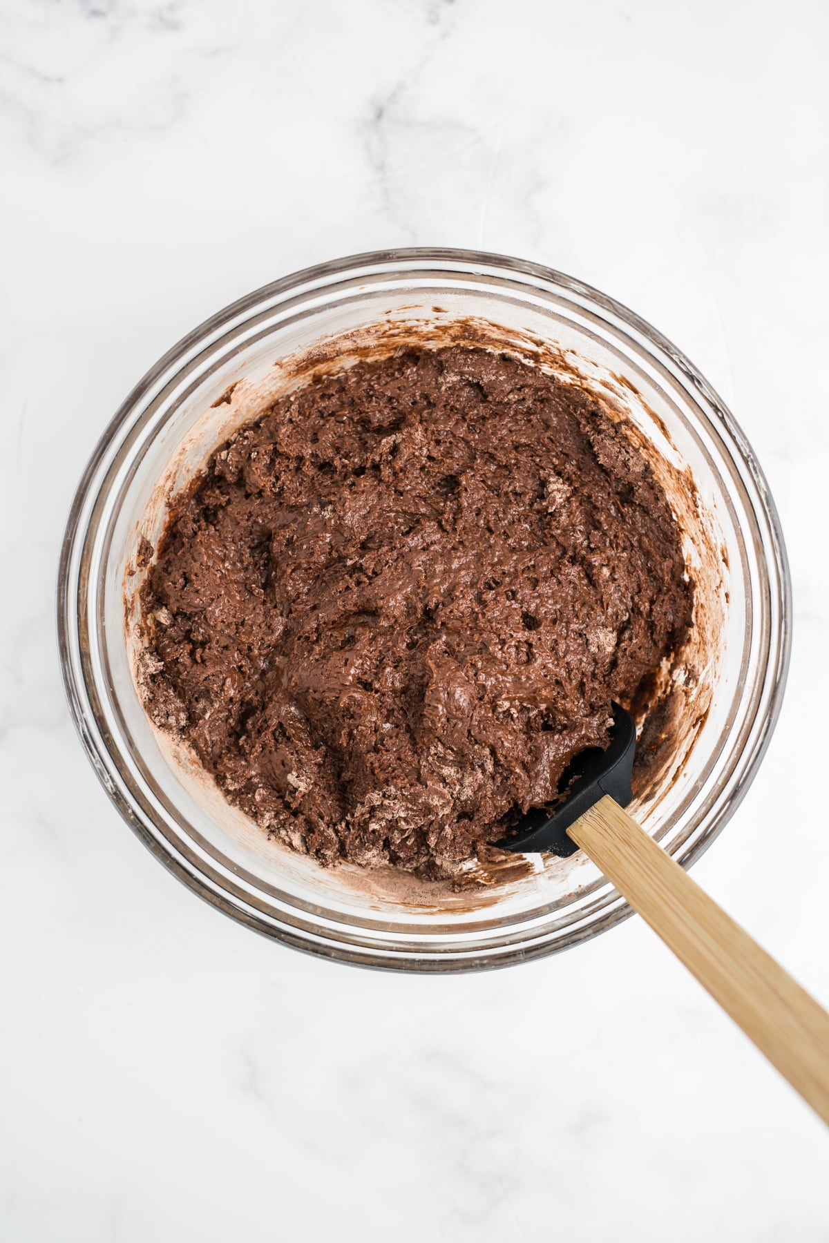 Wet and dry ingredients for the muffins combined in a glass bowl.