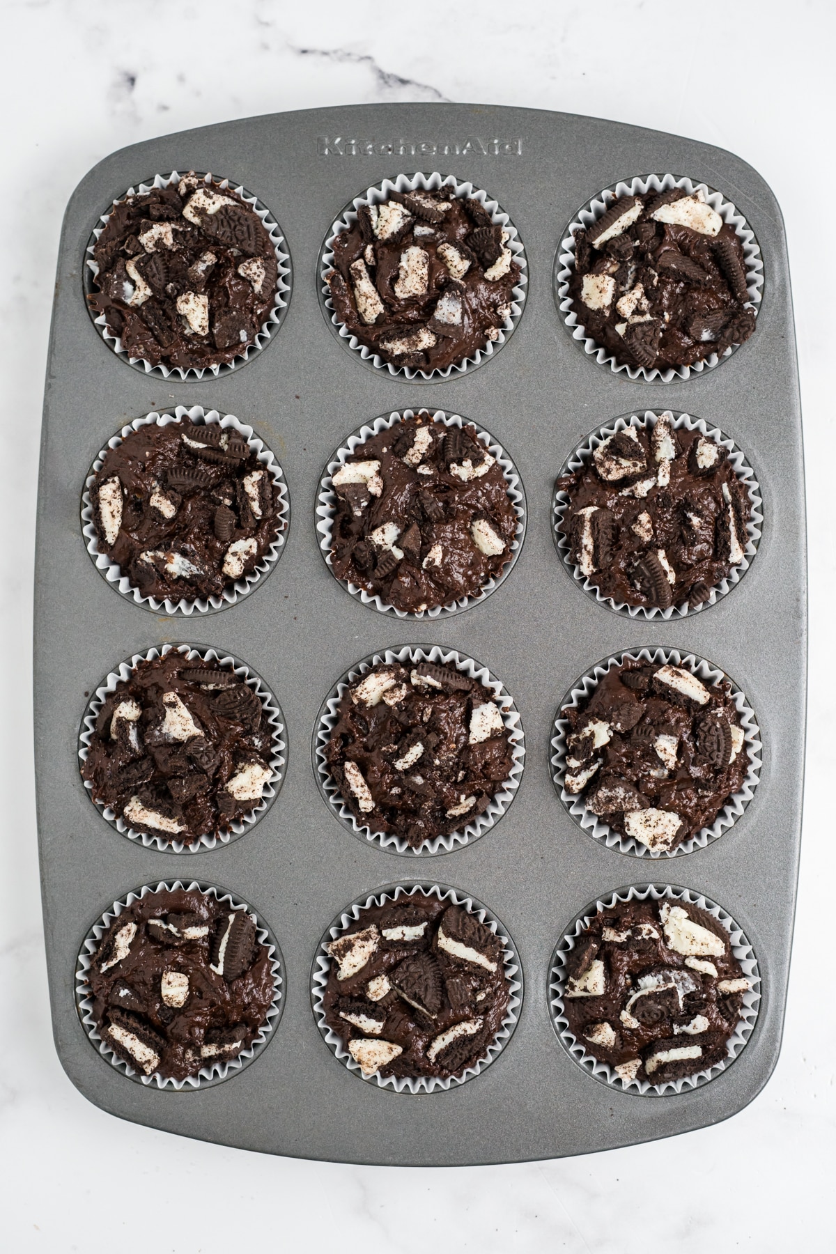 Oreos added to the muffin batter in the muffin tin.