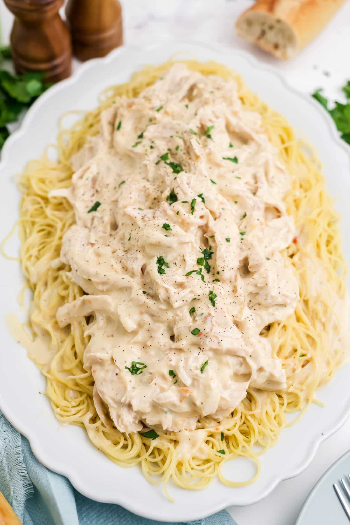 Crockpot angel chicken over noodles on a white oval platter.