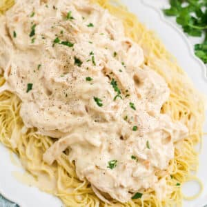 Slow cooker angel chicken shredded on a plate of pasta.
