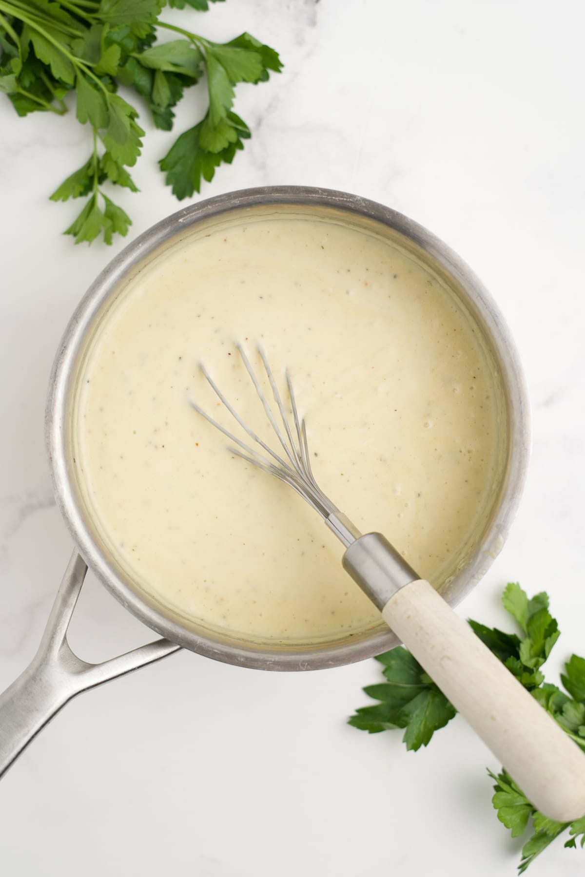 Angel chicken sauce cooked in a saucepan with a whisk resting to the side. 