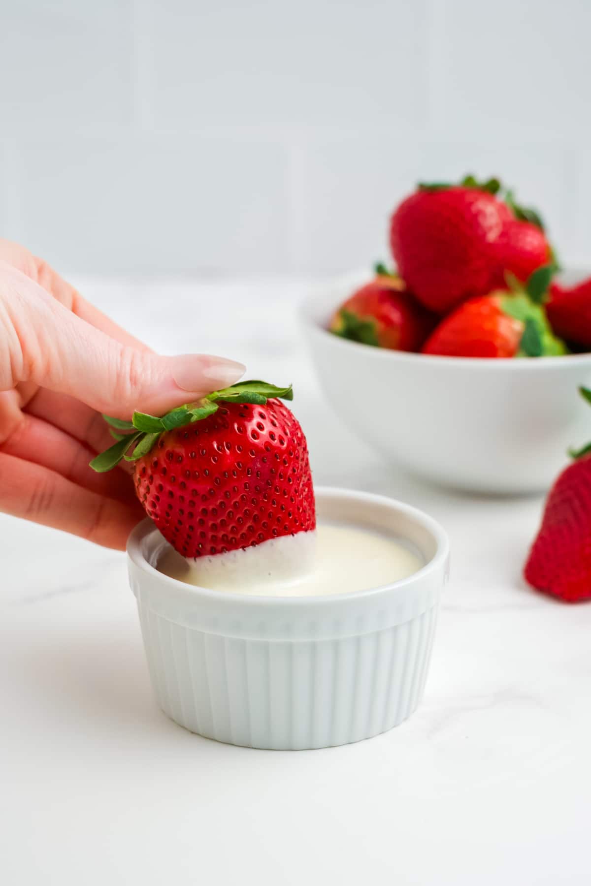 A strawberry being dipped into white chocolate. 