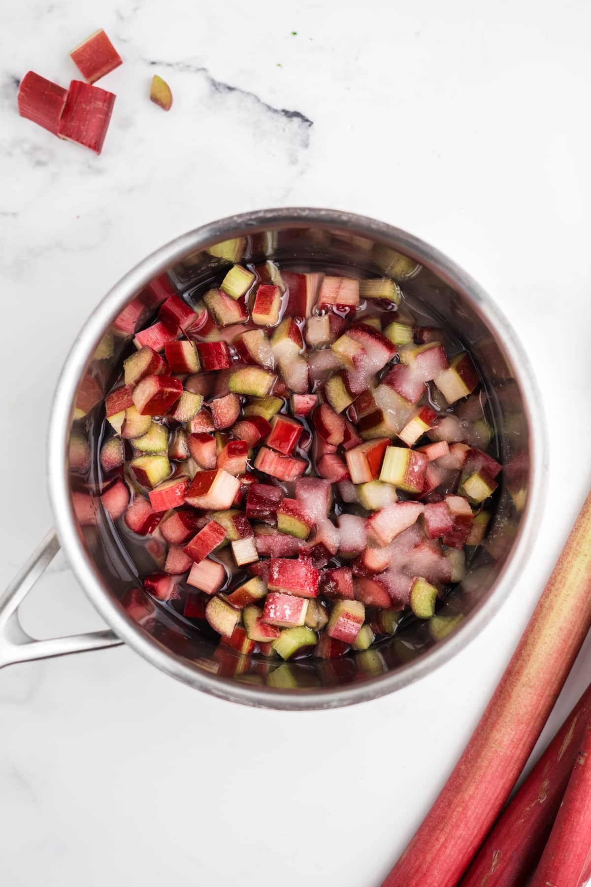 Rhubarb and sugar simmering in a saucepan.