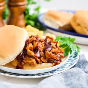 Slow cooker pulled pork tenderloin on a bun on a plate.