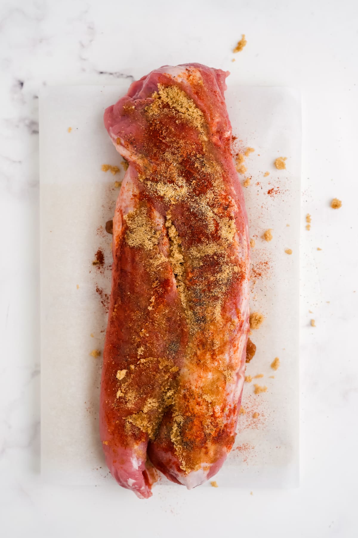 A seasoned pork tenderloin on a cutting board.