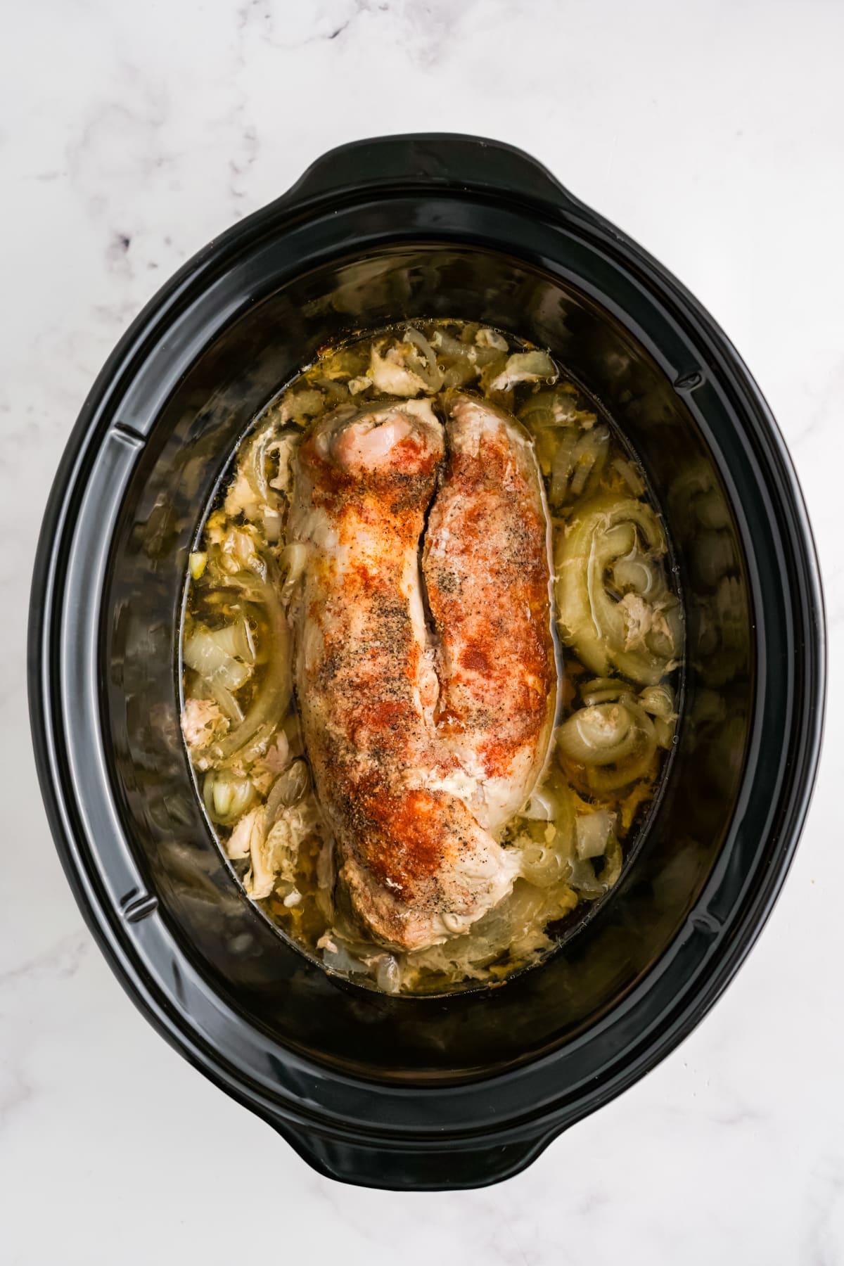 Pulled pork tenderloin ingredients in a slow cooker after cooking.