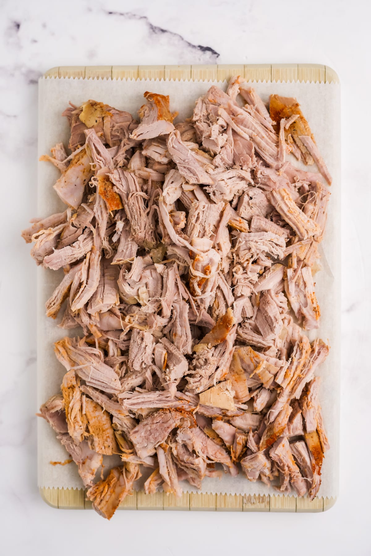 Shredded pork tenderloin on a cutting board.