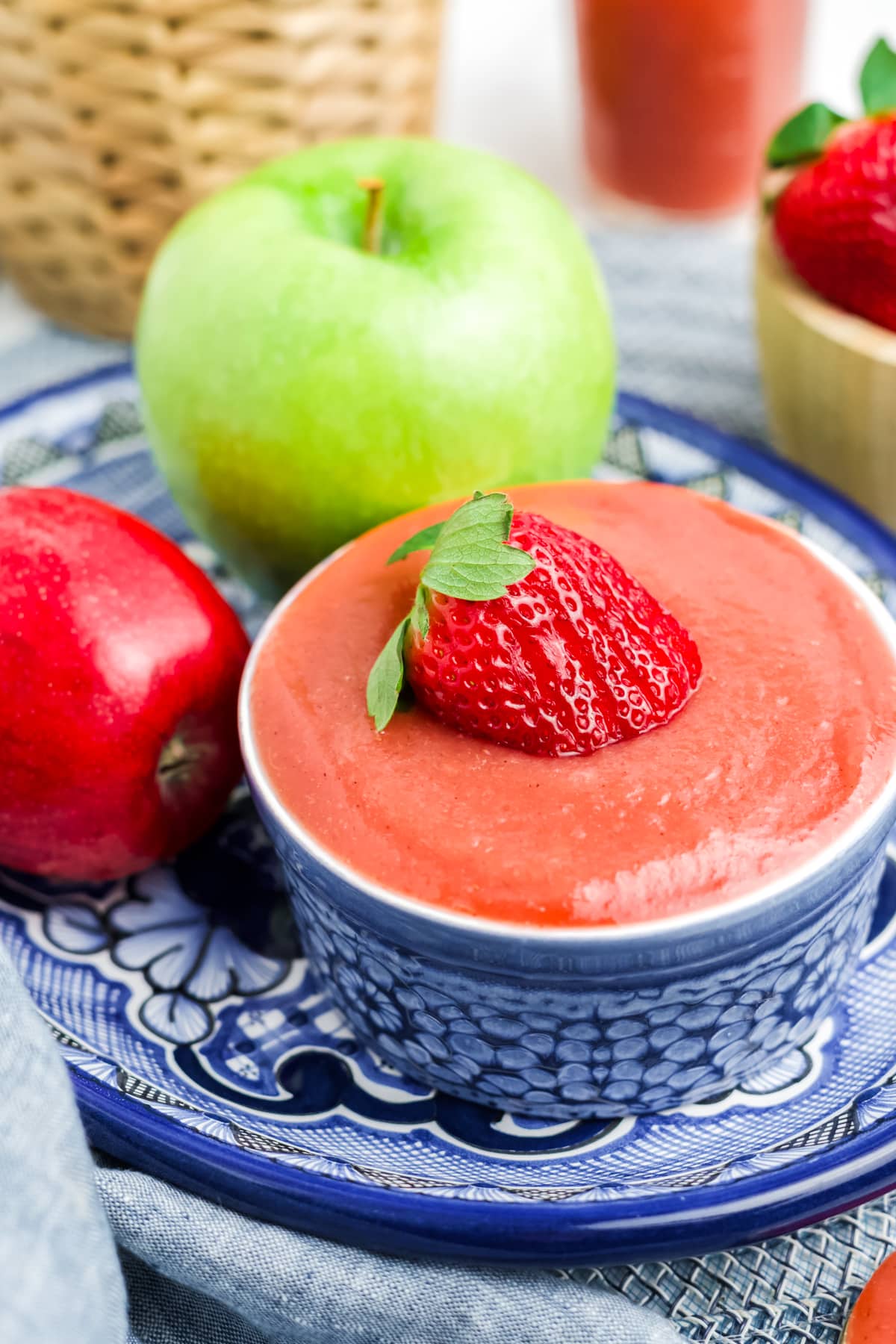 Strawberry applesauce in a blue and white dish garnished with a strawberry on top. 