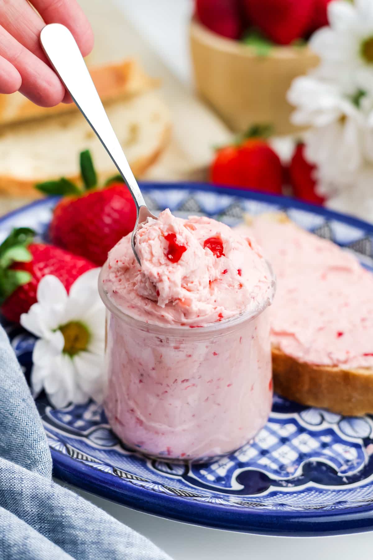 Strawberry butter in a jar on a white and blue plate. 