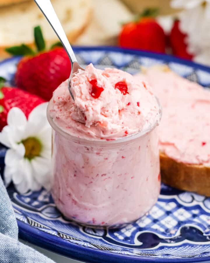 Strawberry butter in a jar with a spoon dipping into the jar.