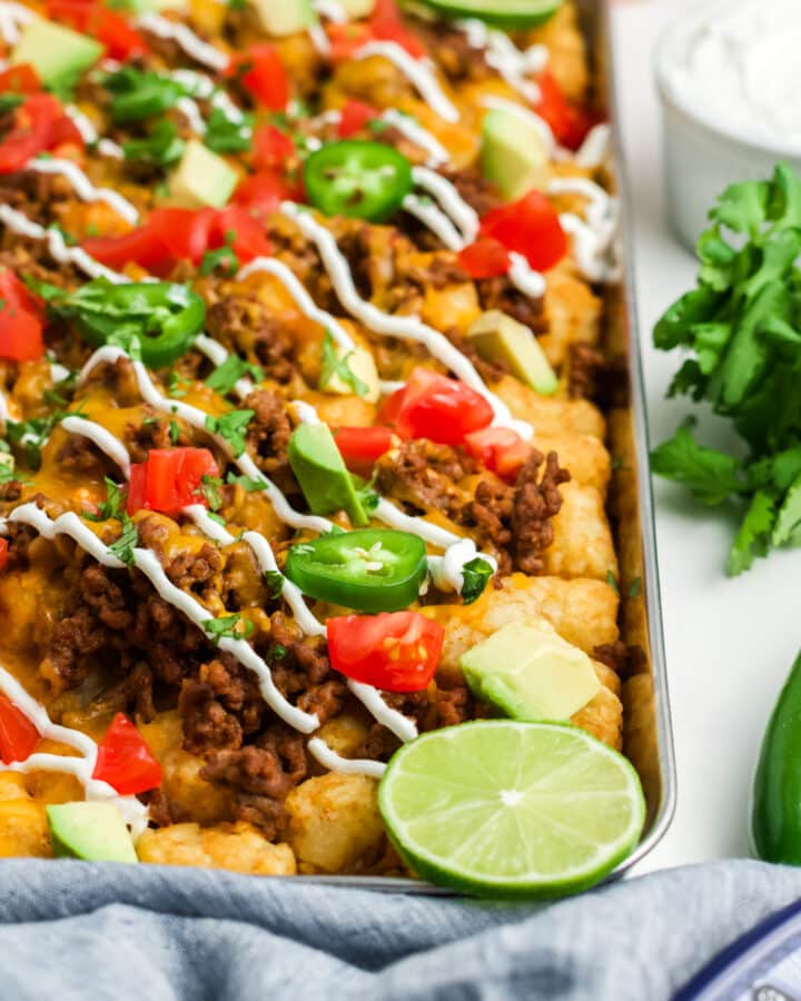 Totchos on a baking sheet garnished with lime slices.