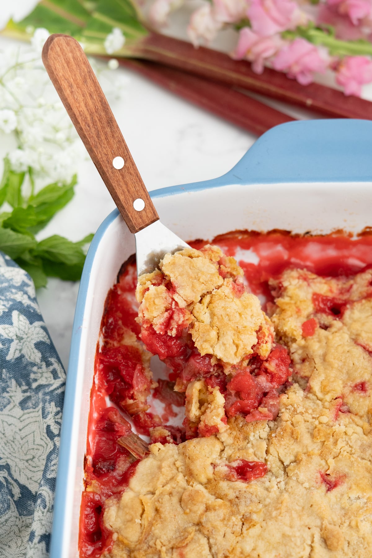 A spoon scooping out a portion of rhubarb dump cake from the baking dish. 