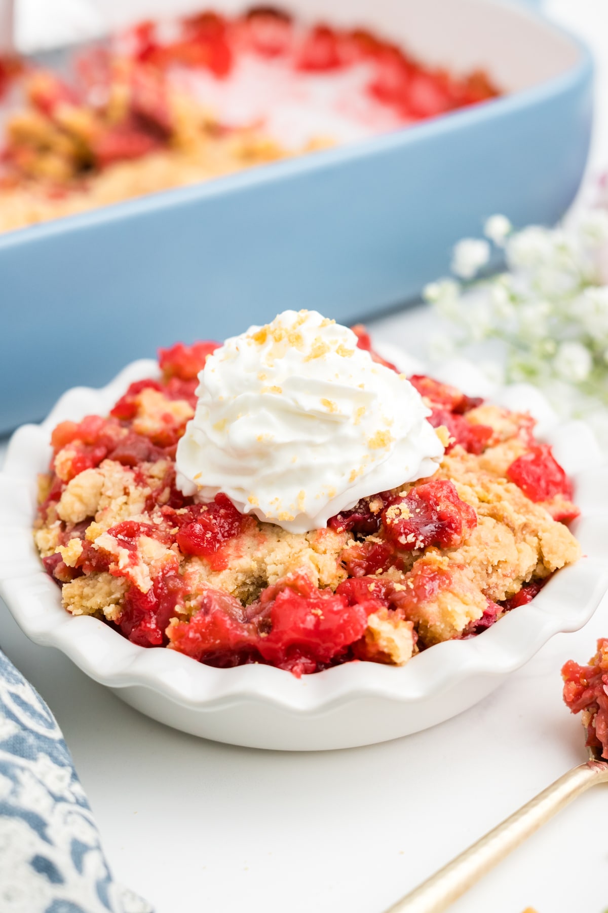 Rhubarb dump cake in a white dish in front of a casserole dish of more. 