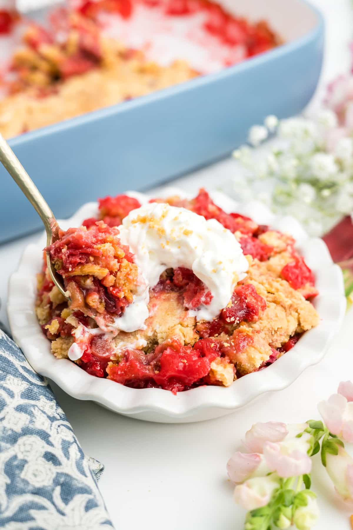A spoonful of rhubarb cake held up over a dish of more. 