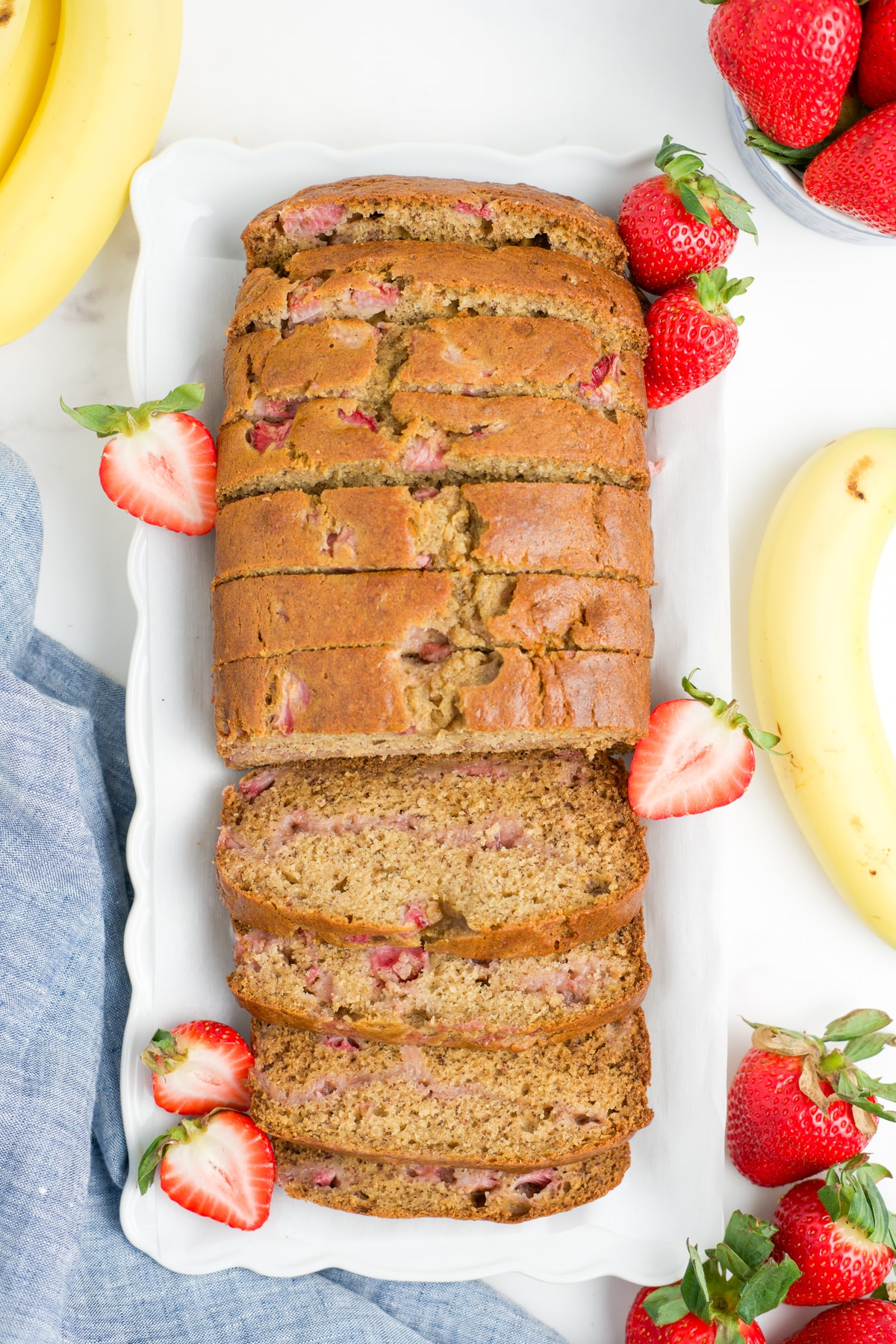 An entire loaf of strawberry banana bread sliced up on a platter.