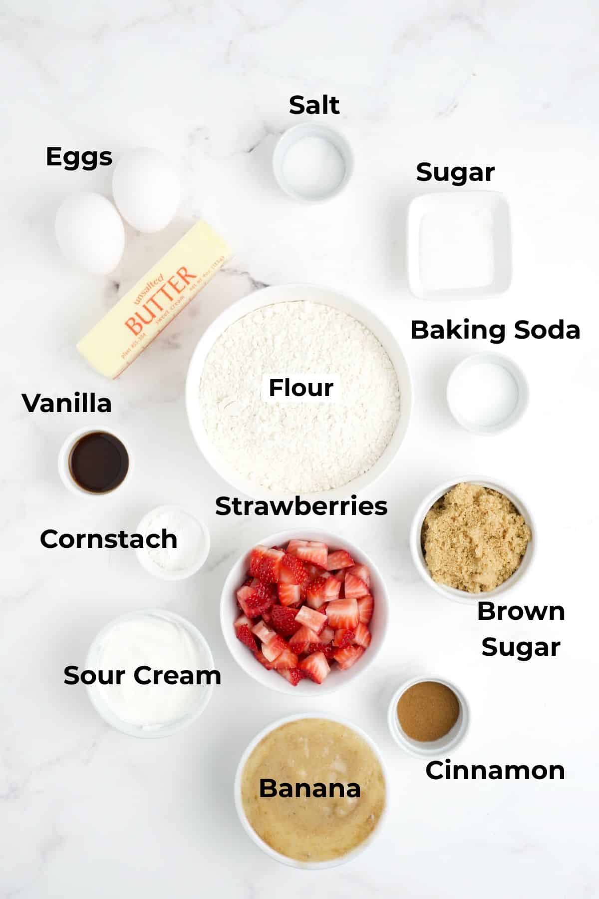 Ingredients to make strawberry banana bread in bowls on a table.