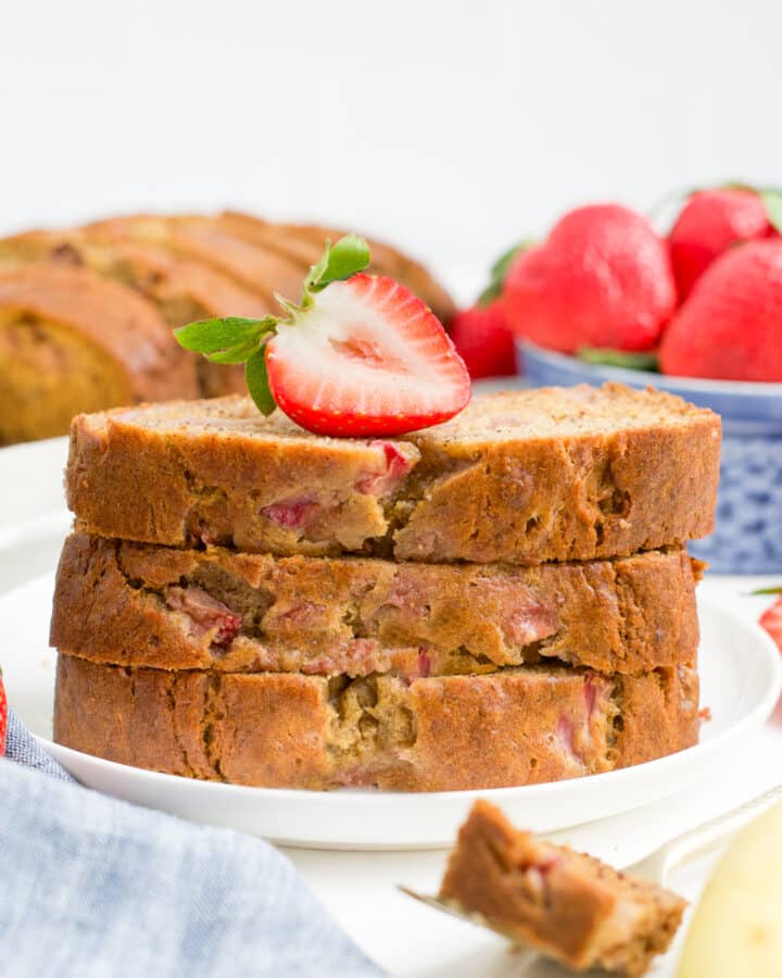 A plate of strawberry banana bread with a strawberry on top.