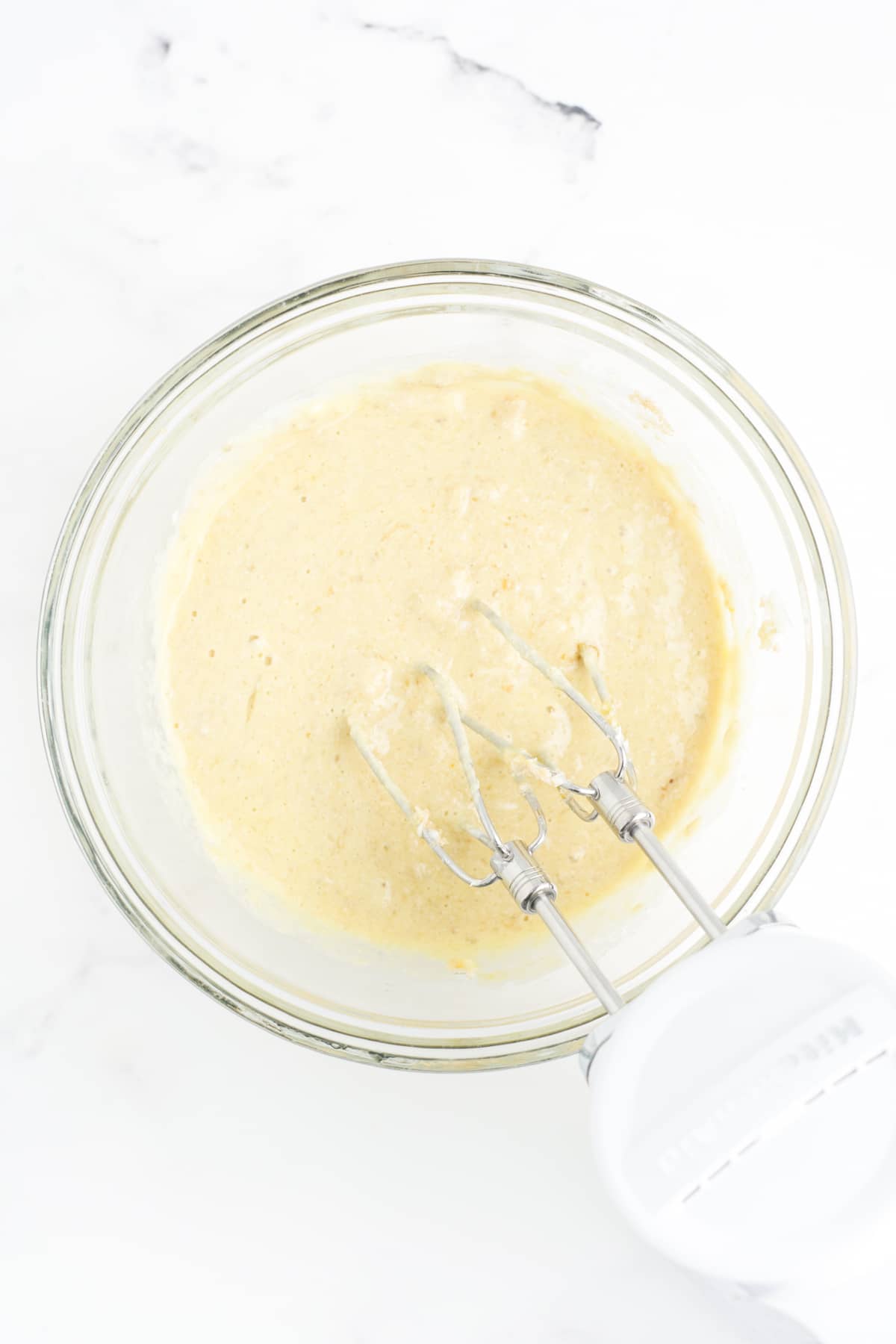 Eggs, sour cream, vanilla extract, and mashed bananas being mixed.