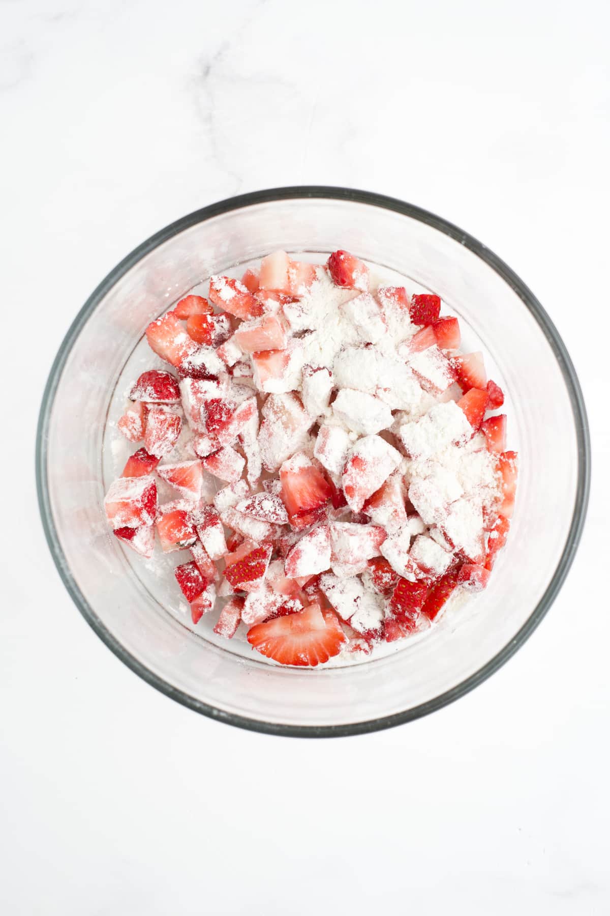Flour and strawberries tossed in a bowl.