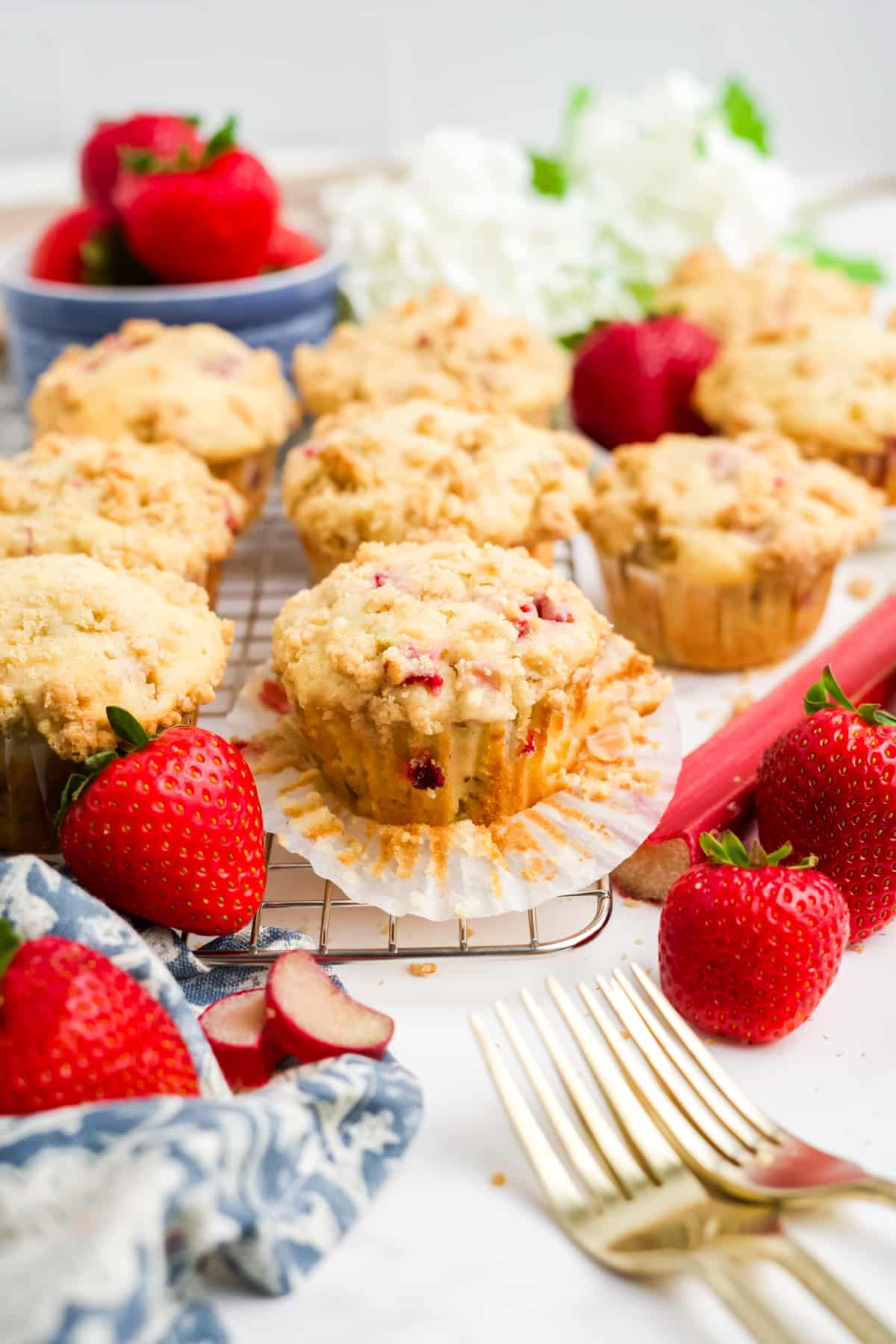Strawberry and rhubarb muffins on a cooling rack with fresh strawberries. 