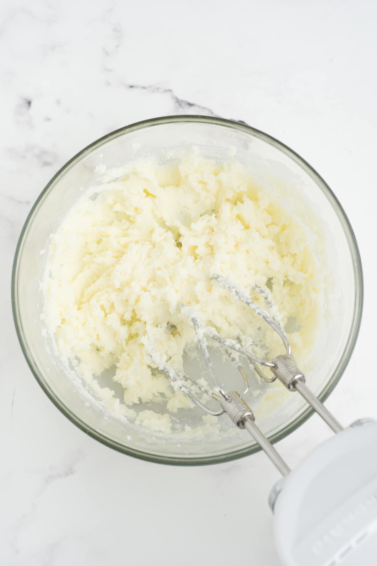 Sugar and butter creamed in a mixing bowl with electric mixer.