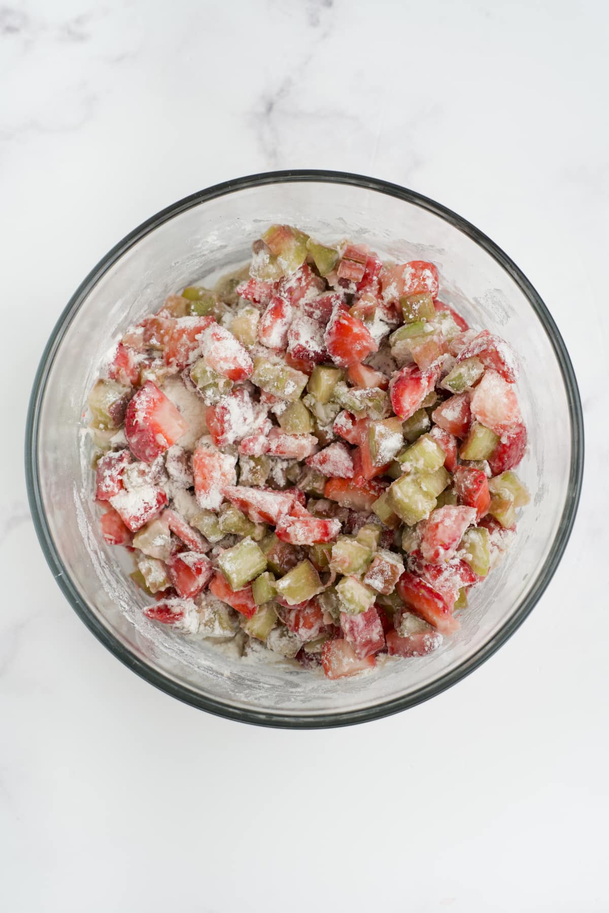 Strawberries and rhubarb mixed with flour in a bowl. 