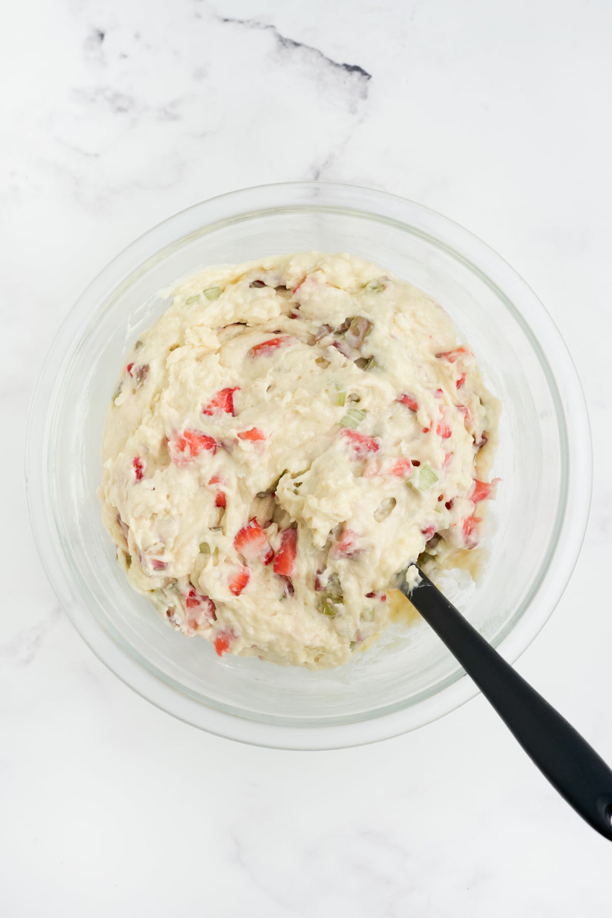 Strawberry rhubarb muffin batter mixed in a bowl. 