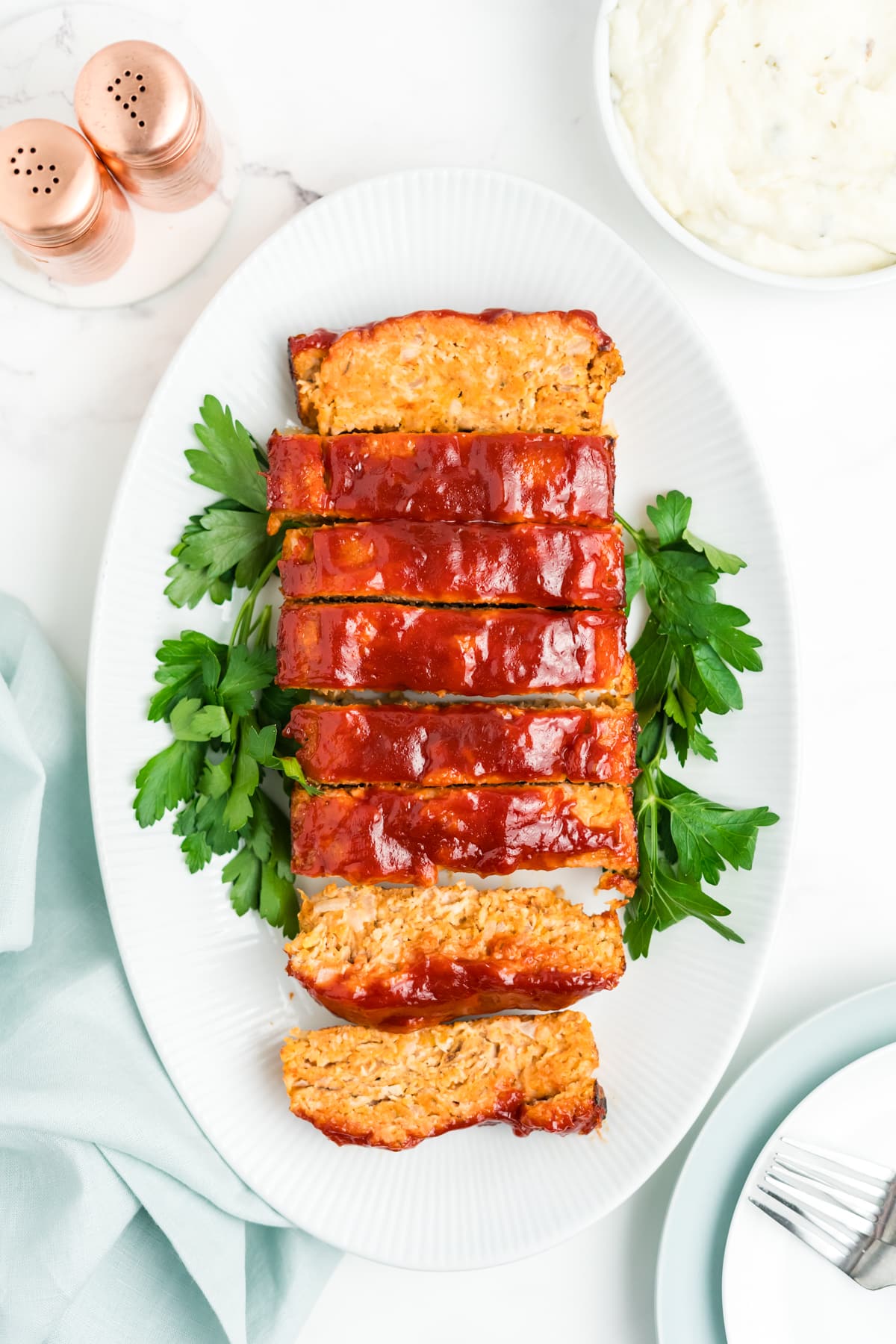 Chicken meatloaf, sliced up on a plate and garnished with parsley.
