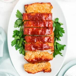 Slices of ground chicken meatloaf on a white serving plate.