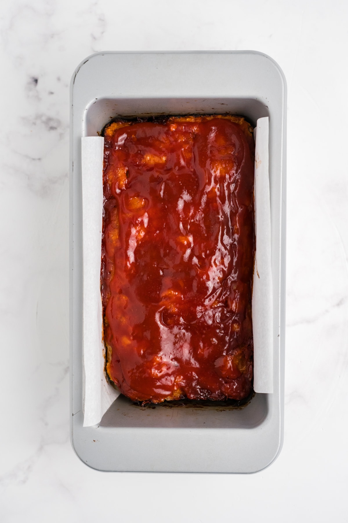 The glazed chicken meatloaf cooked and cooling in a prepared loaf pan.