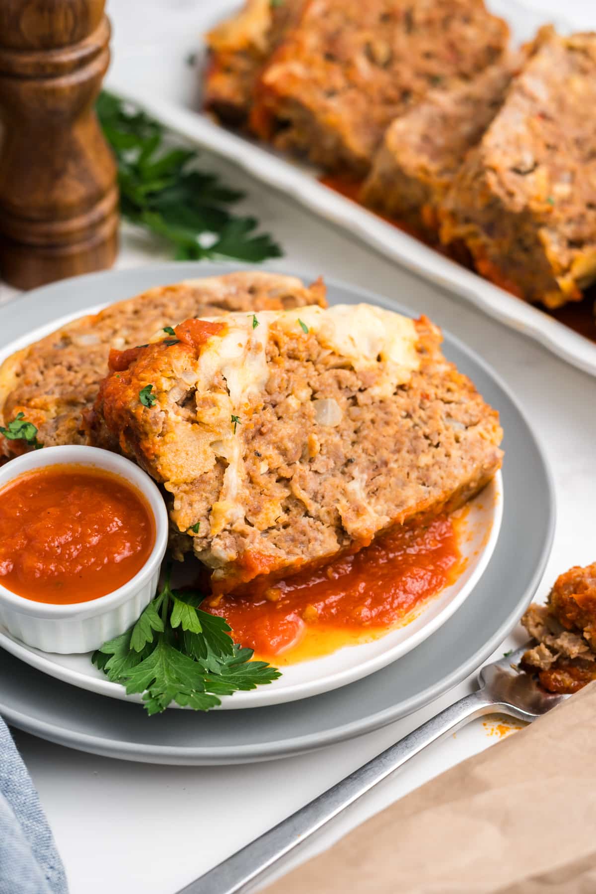 Slices of Italian meatloaf on a plate with marinara sauce. 