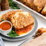 A plate of Italian meatloaf with a side of sauce.