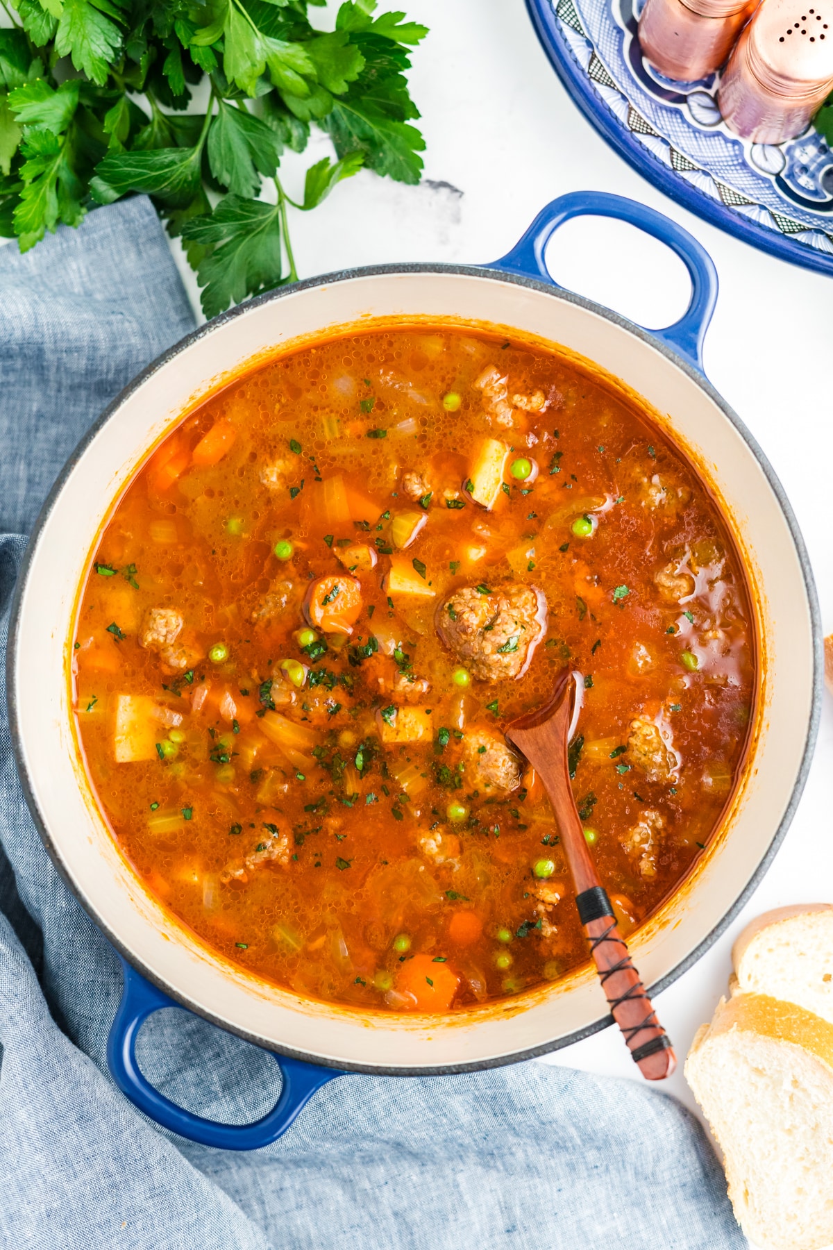 A pot filled with meatball stew and a wooden spoon resting in the pot.