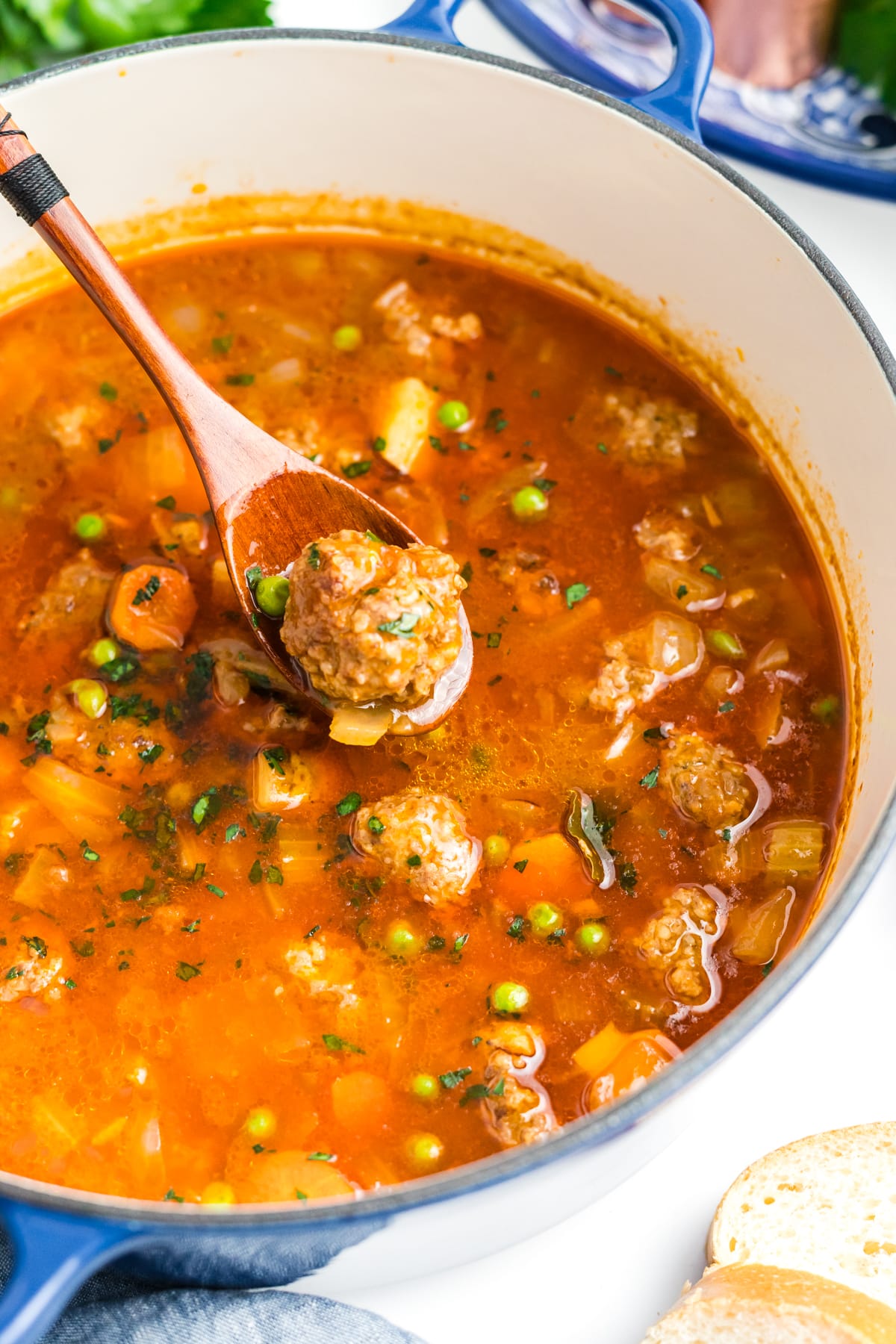 A wooden spoon scooping out meatballs out of a stew.