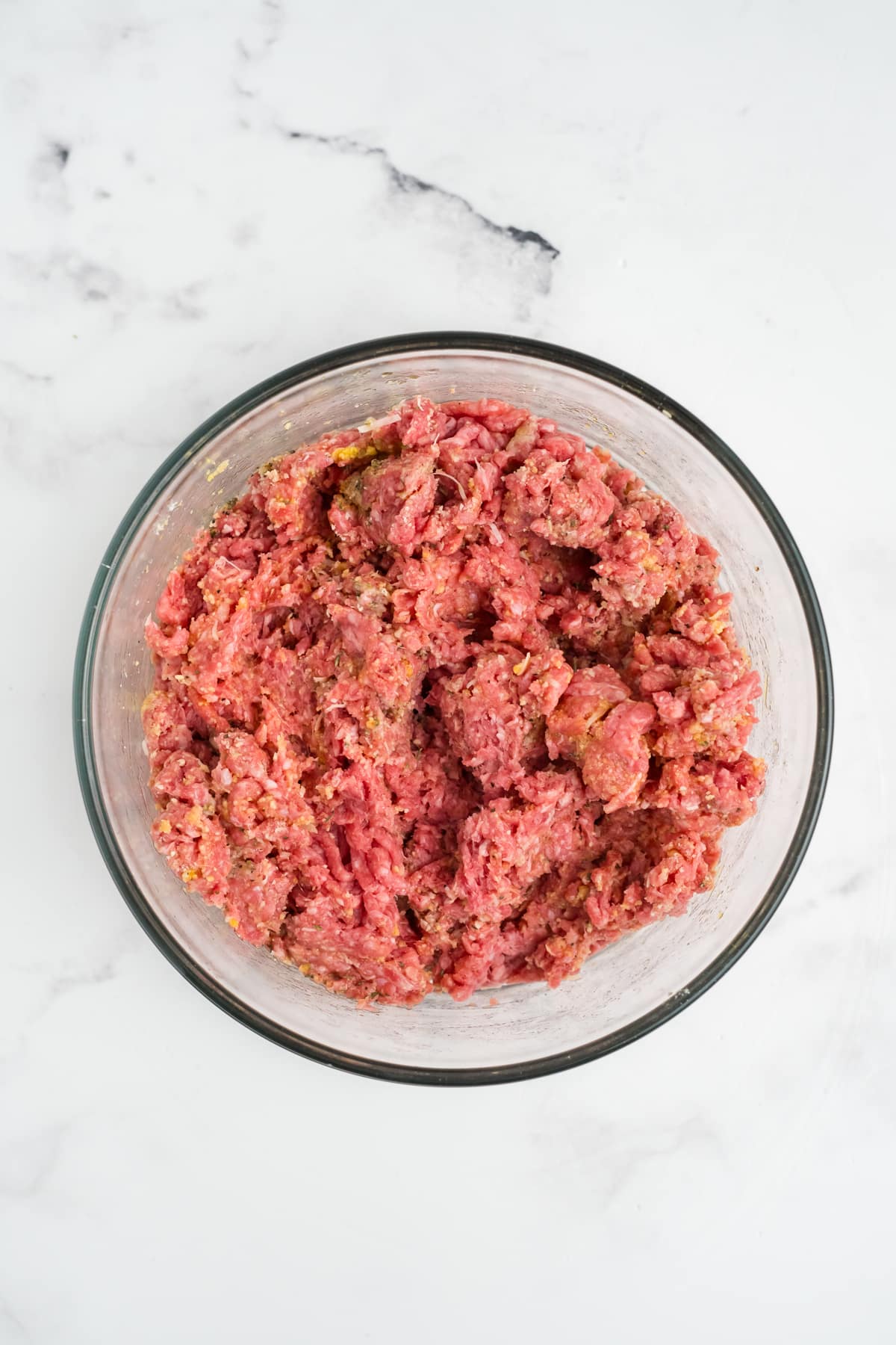 Ground beef, egg, milk, breadcrumbs, Parmesan, and seasonings in a mixing bowl.