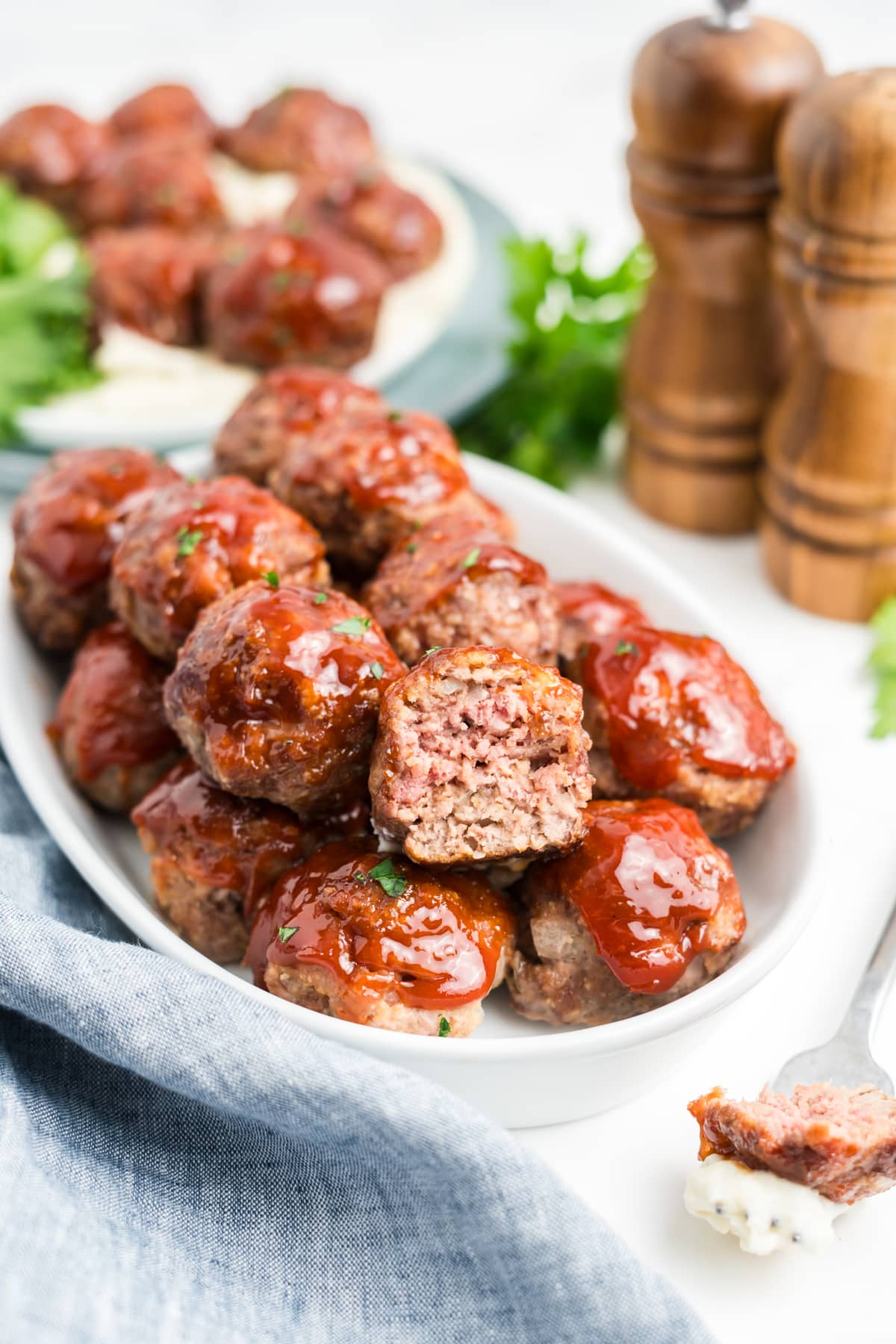 A platter filled with meatloaf meatballs with one meatball broken open.