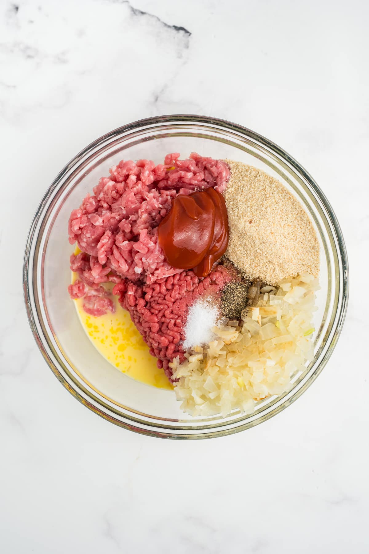 Ground meat, breadcrumbs, sauteed aromatics, ketchup, Worcestershire sauce, and seasonings mixed into the milk and egg mixture.