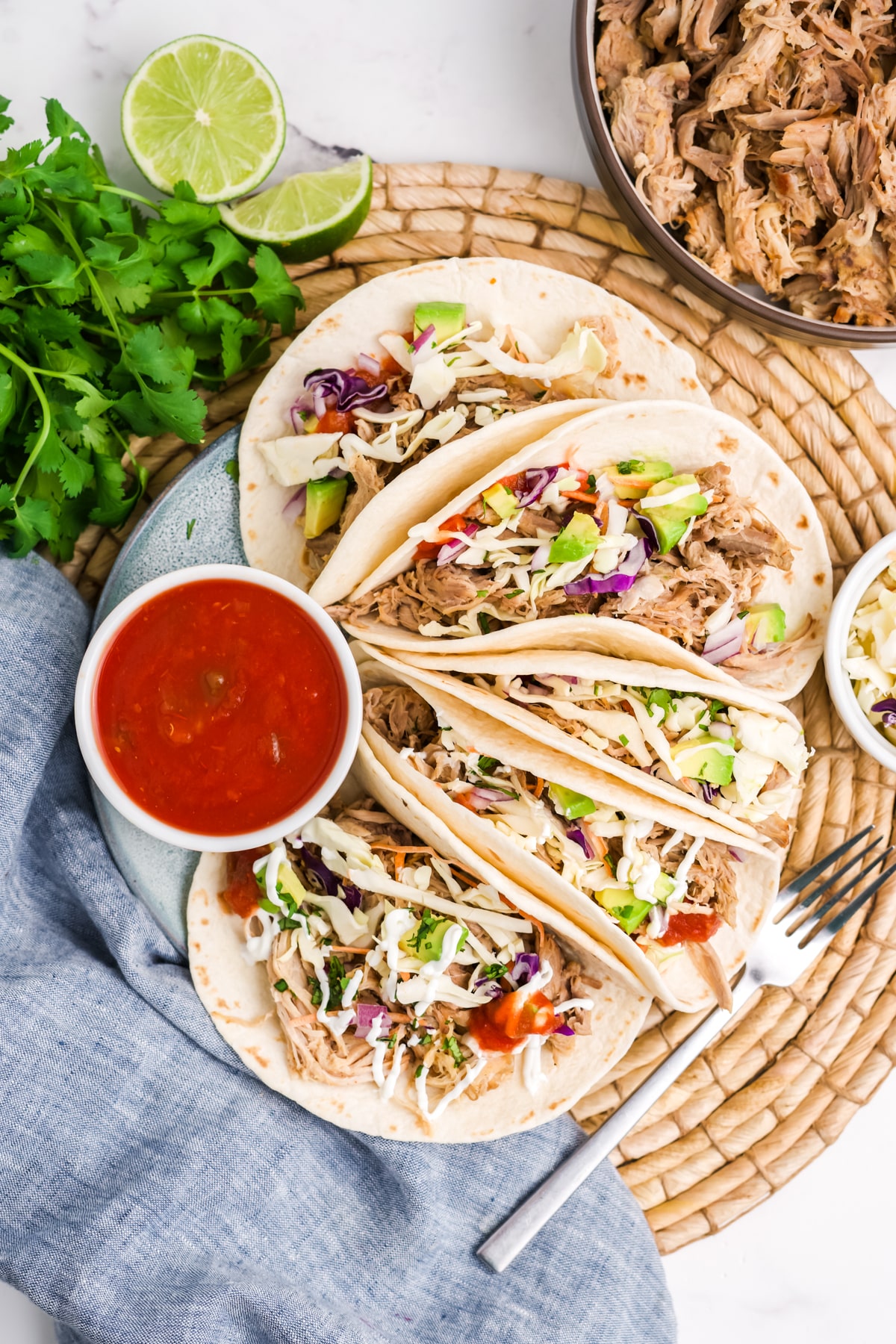 Slow cooker pork tacos on a plate with a ramekin of red salsa. 