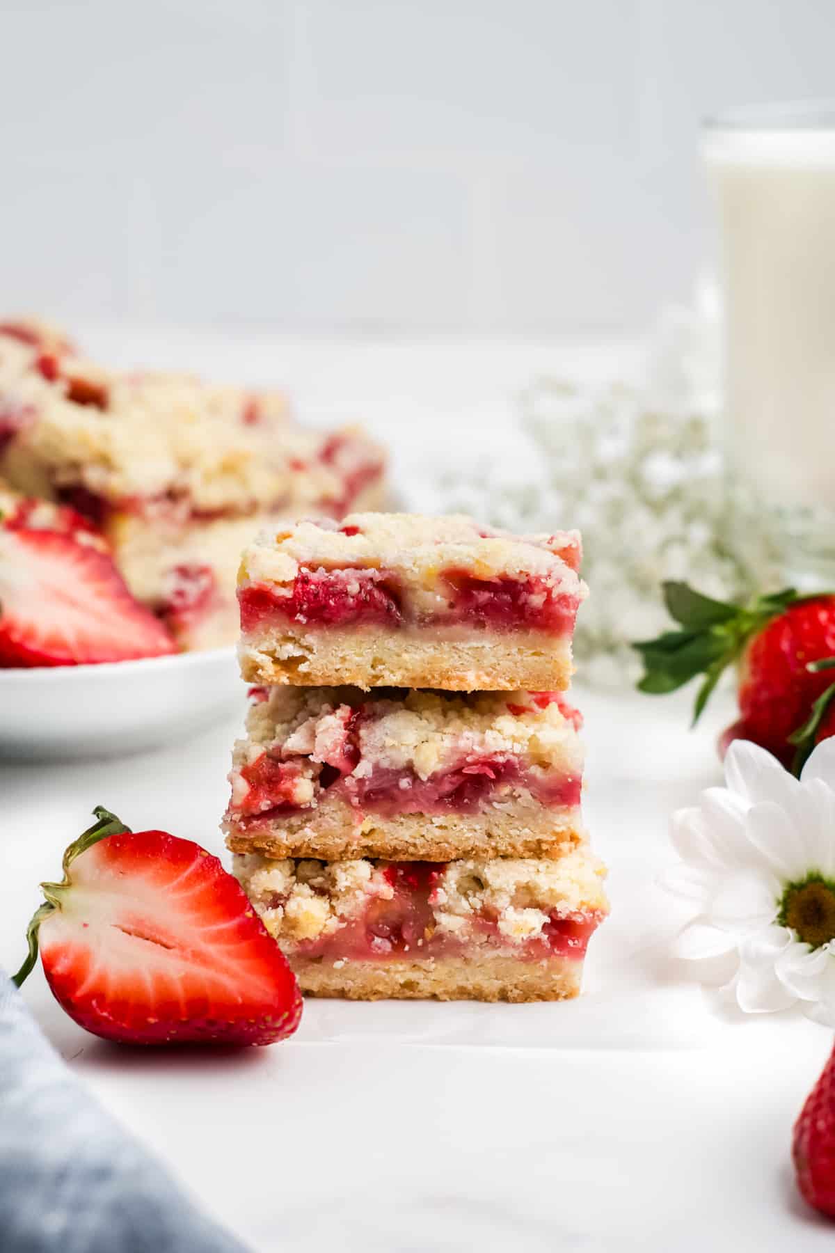 Three strawberry bars stacked on a table with fresh berries. 
