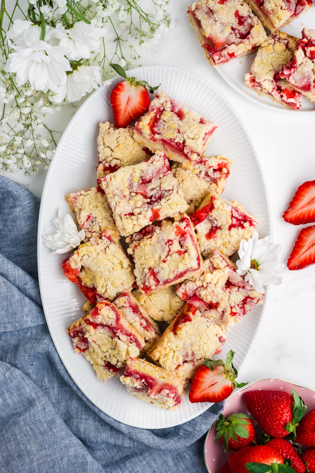 A white plate with strawberry bars with slices of strawberries around it.