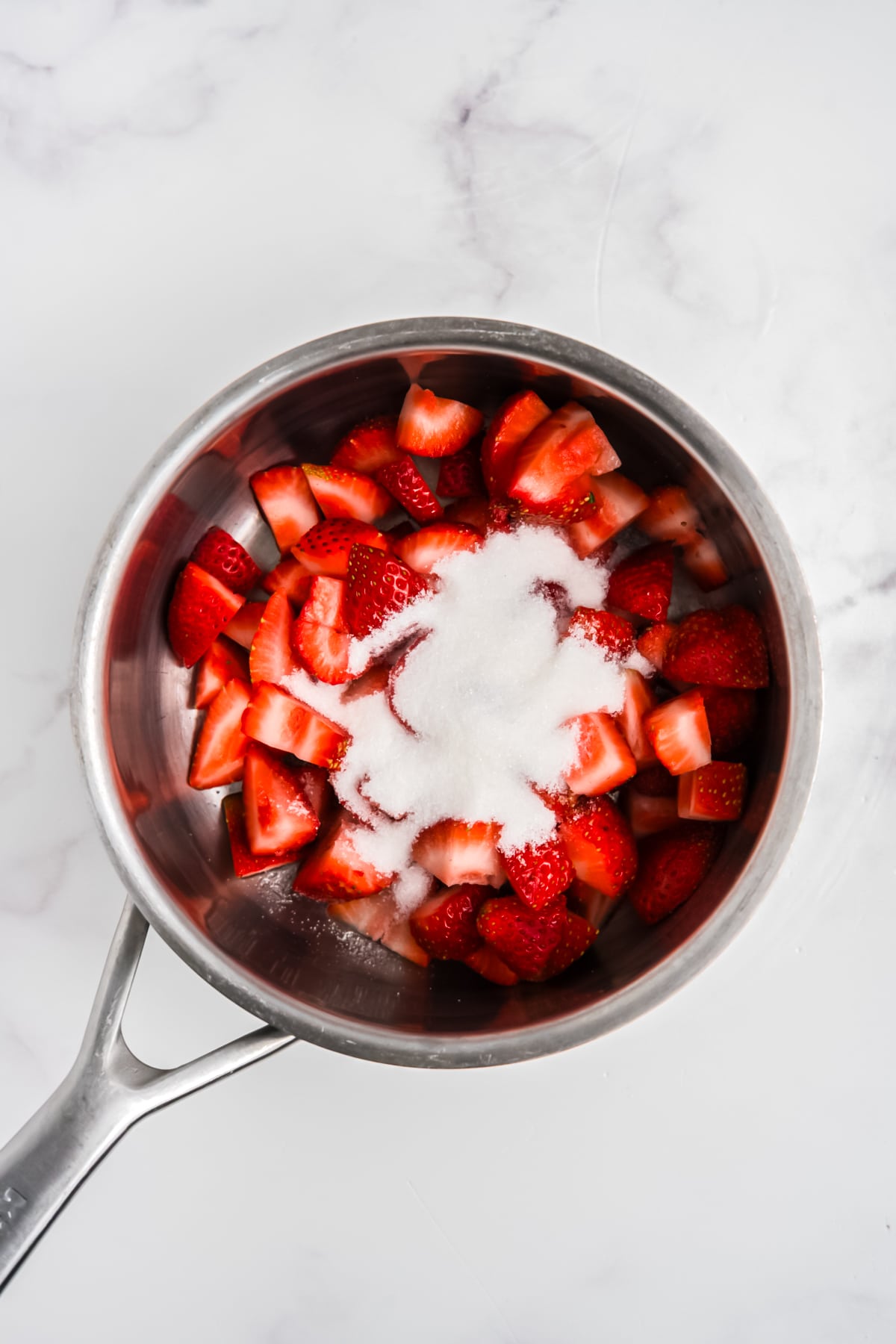 Strawberries and sugar in a saucepan.