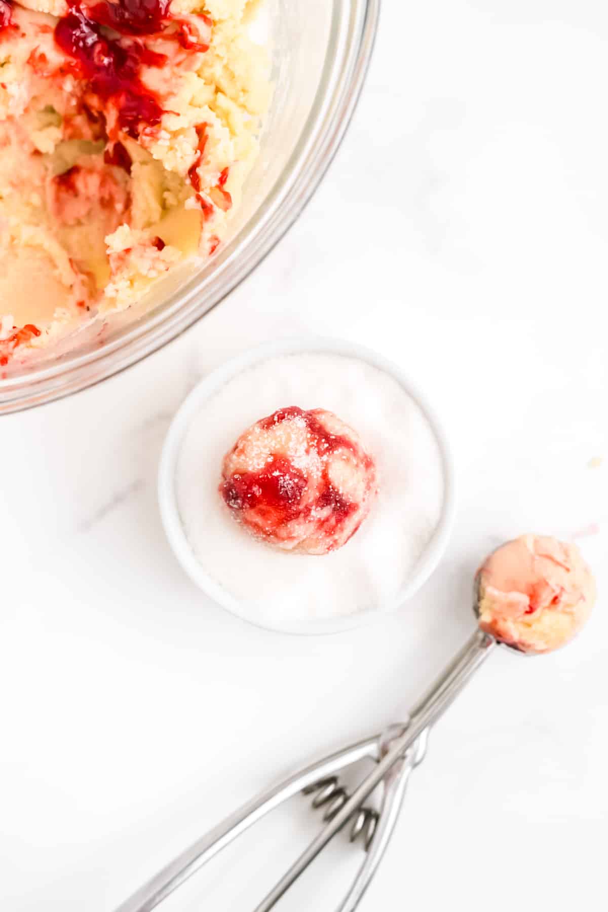The dough balls scooped and added to sugar.